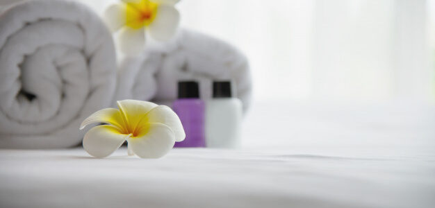 hotel-towel-shampoo-soap-bath-bottle-set-white-bed-with-plumeria-flower-decorated-relax-vacation-hotel-resort-concept_1150-13703
